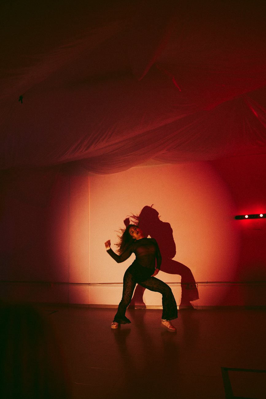 A dancer's silhouette against a glowing orange-red circle of light at PULSE