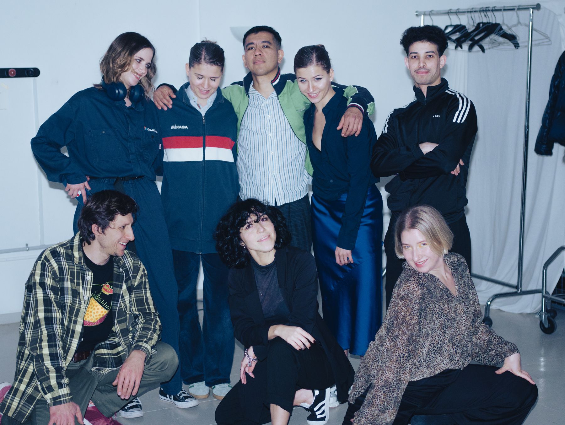 The PULSE team, standing and crouching together in front of a white wall