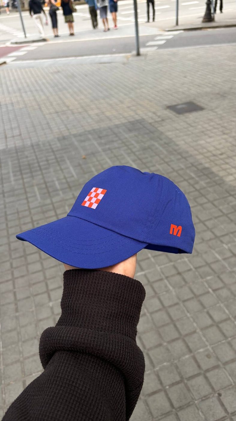 A hand holding up the finished blue cap on a street in Barcelona