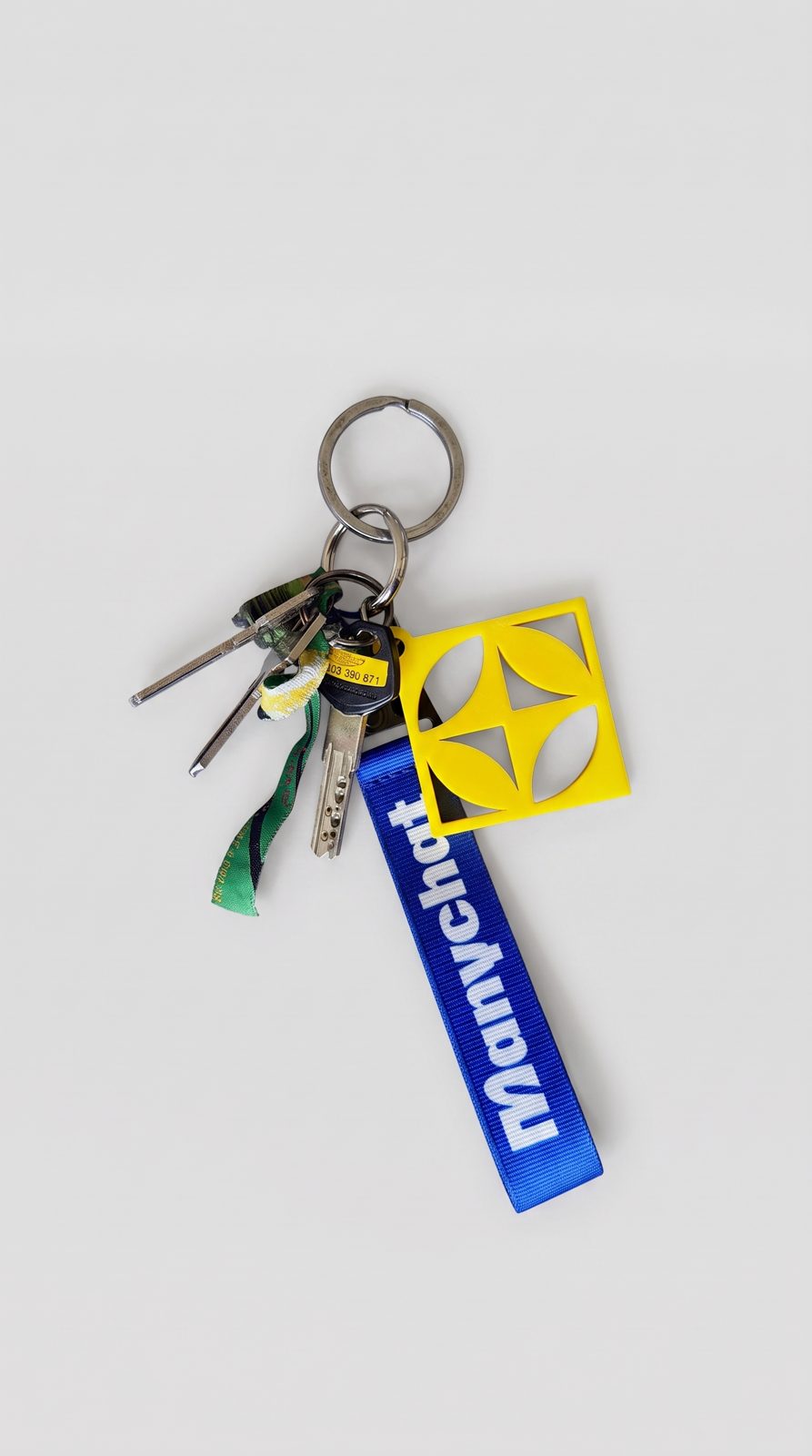 The keychain on a ring of keys: a blue woven strap, a yellow 3D-printed charm and a ring carabiner