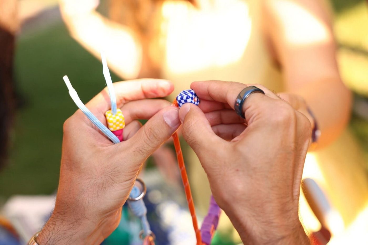 Two hands threading a bead onto a cord
