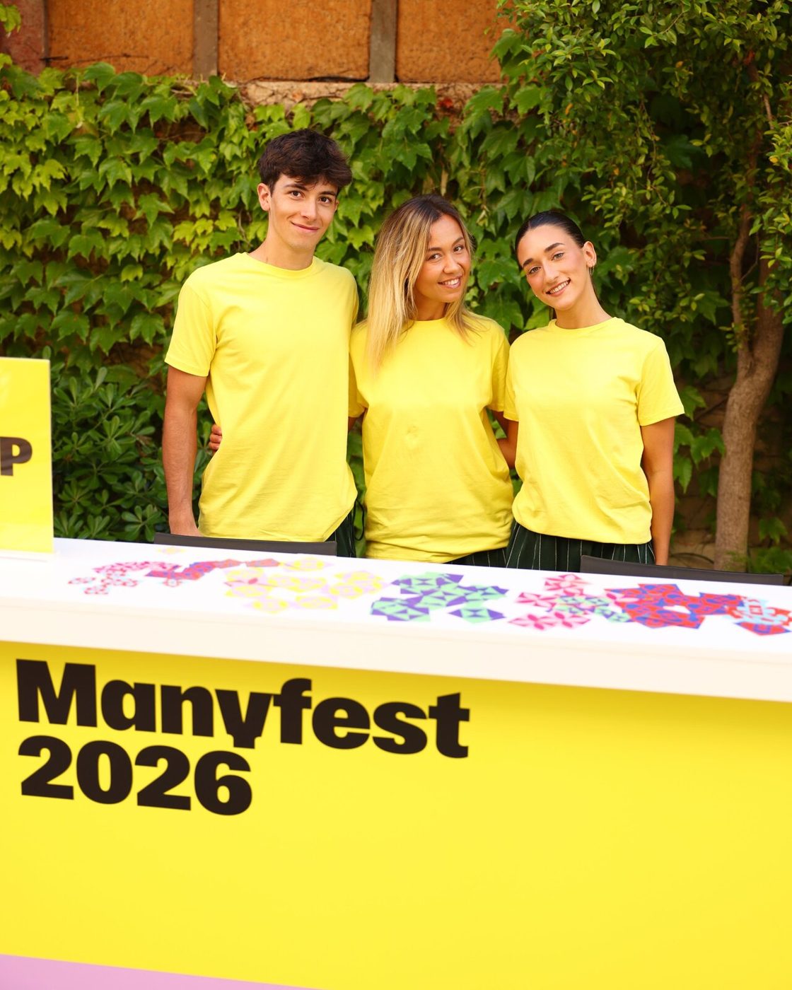 Three crew members in the yellow T-shirts behind the yellow info desk