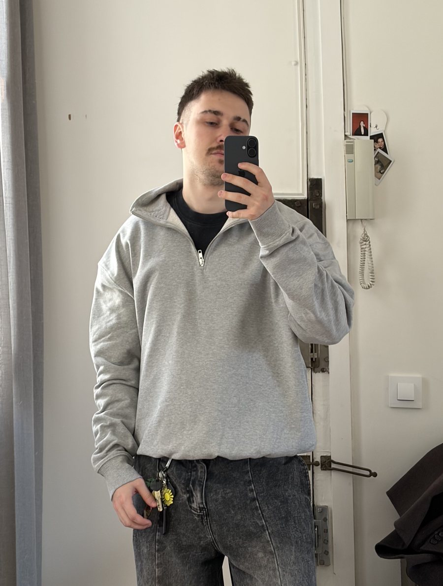 Mirror selfie in the grey quarter-zip, with the festival keychain clipped to the jeans