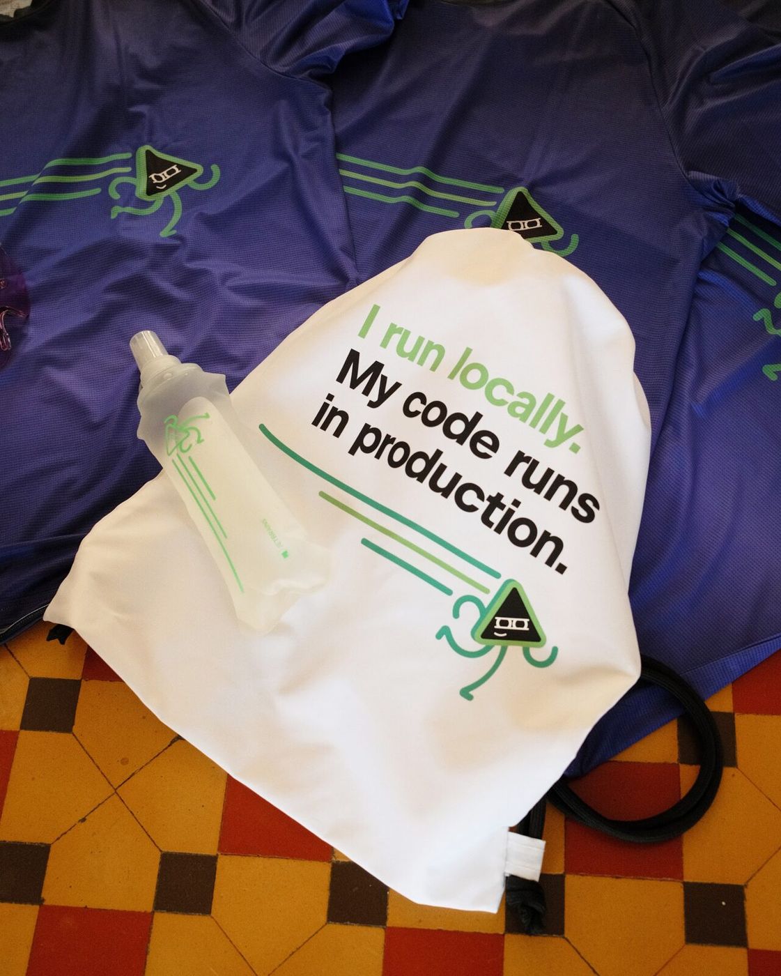 The bag and the flask lying on the violet running tees on a tiled floor
