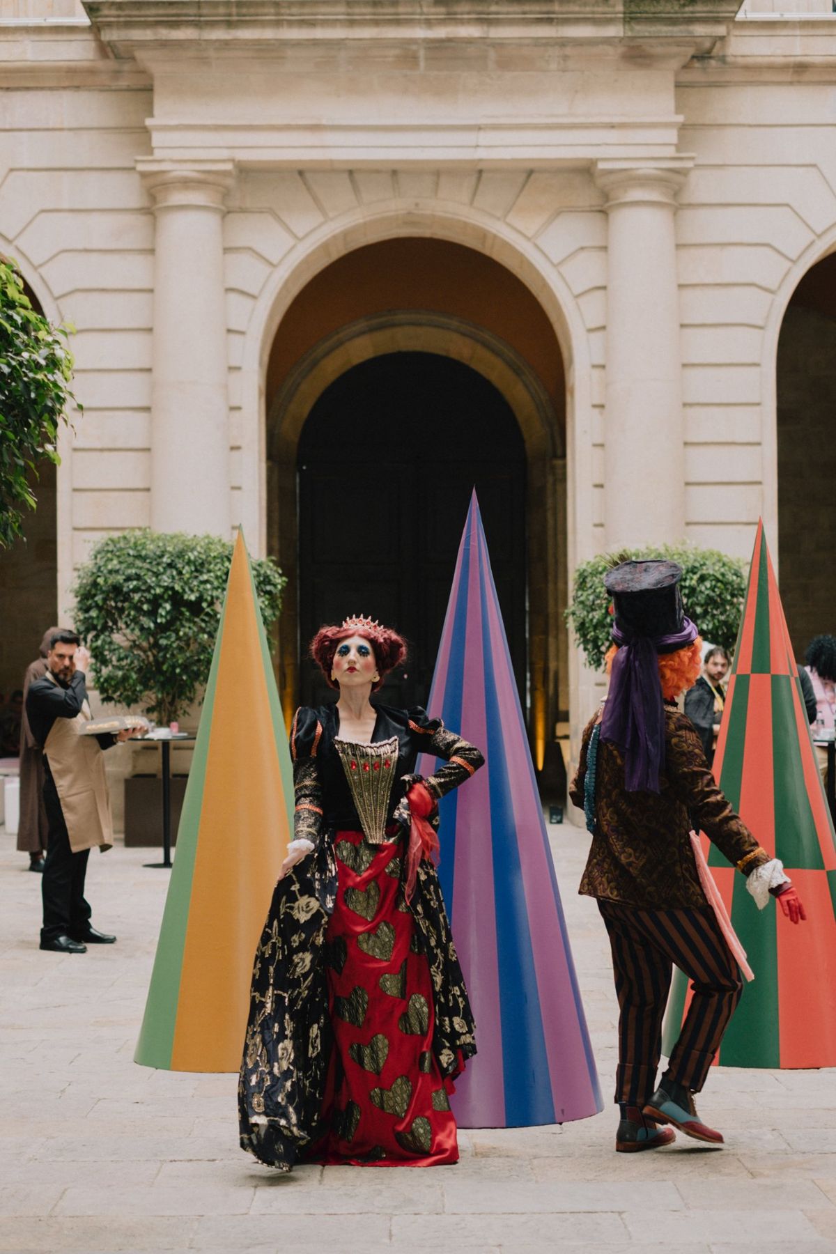Two characters in costume between striped cones