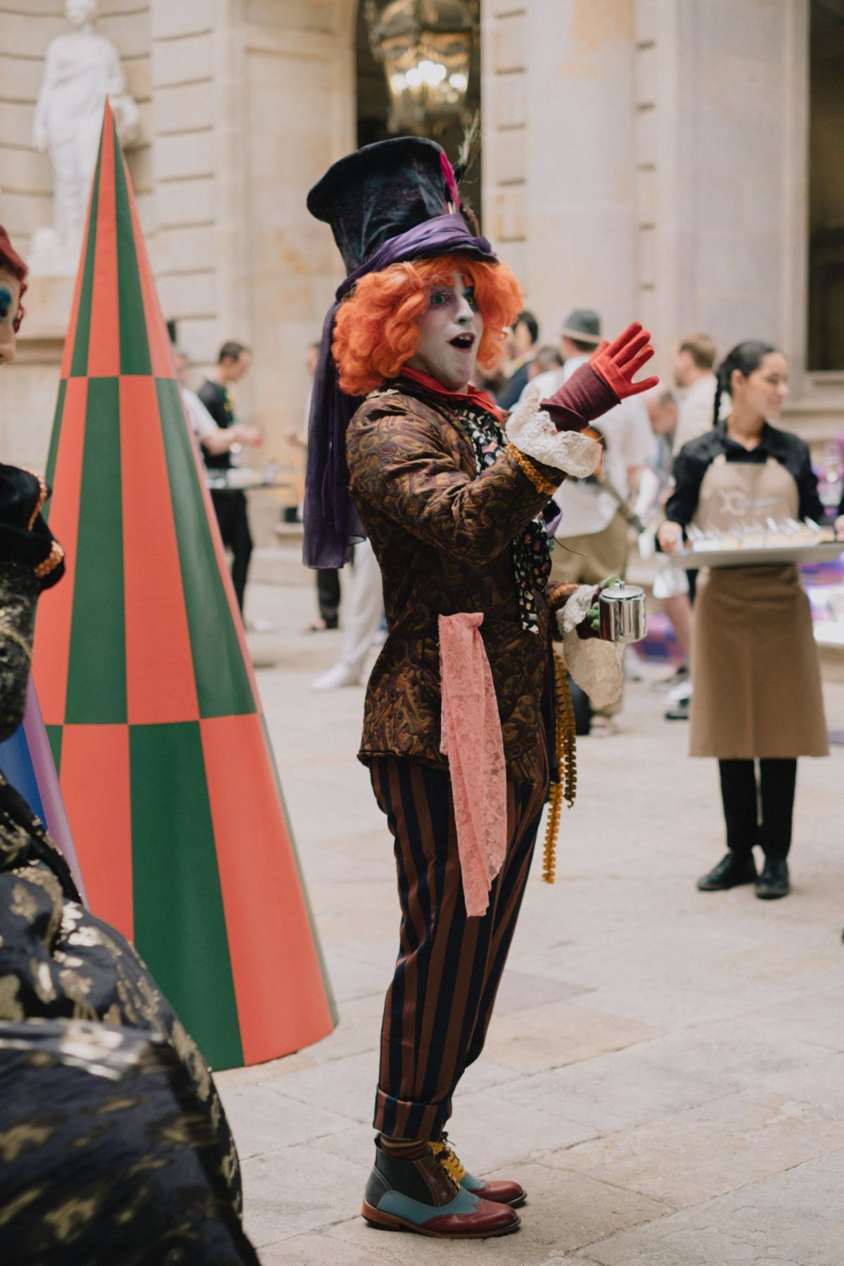 A character in a top hat next to a red and green striped cone