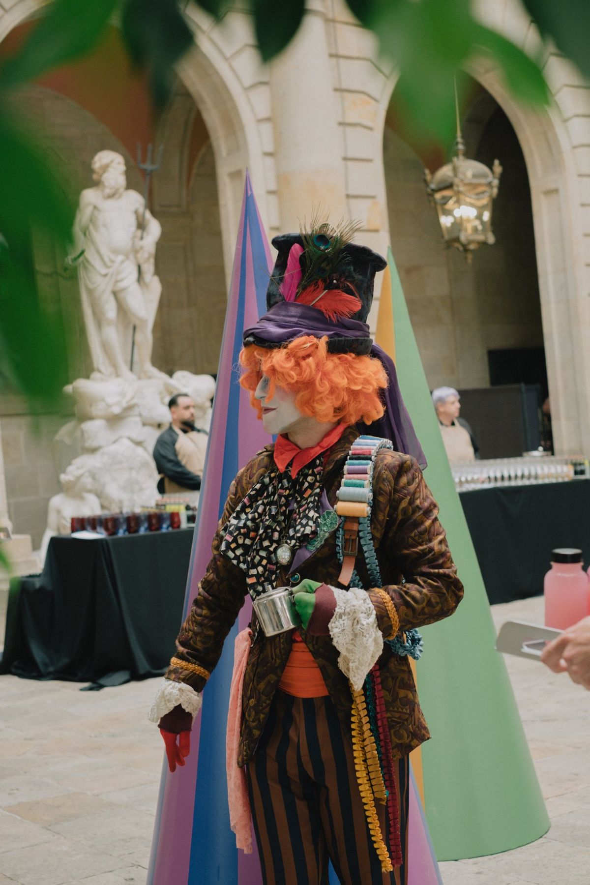 A character in a tall hat and orange wig in the courtyard