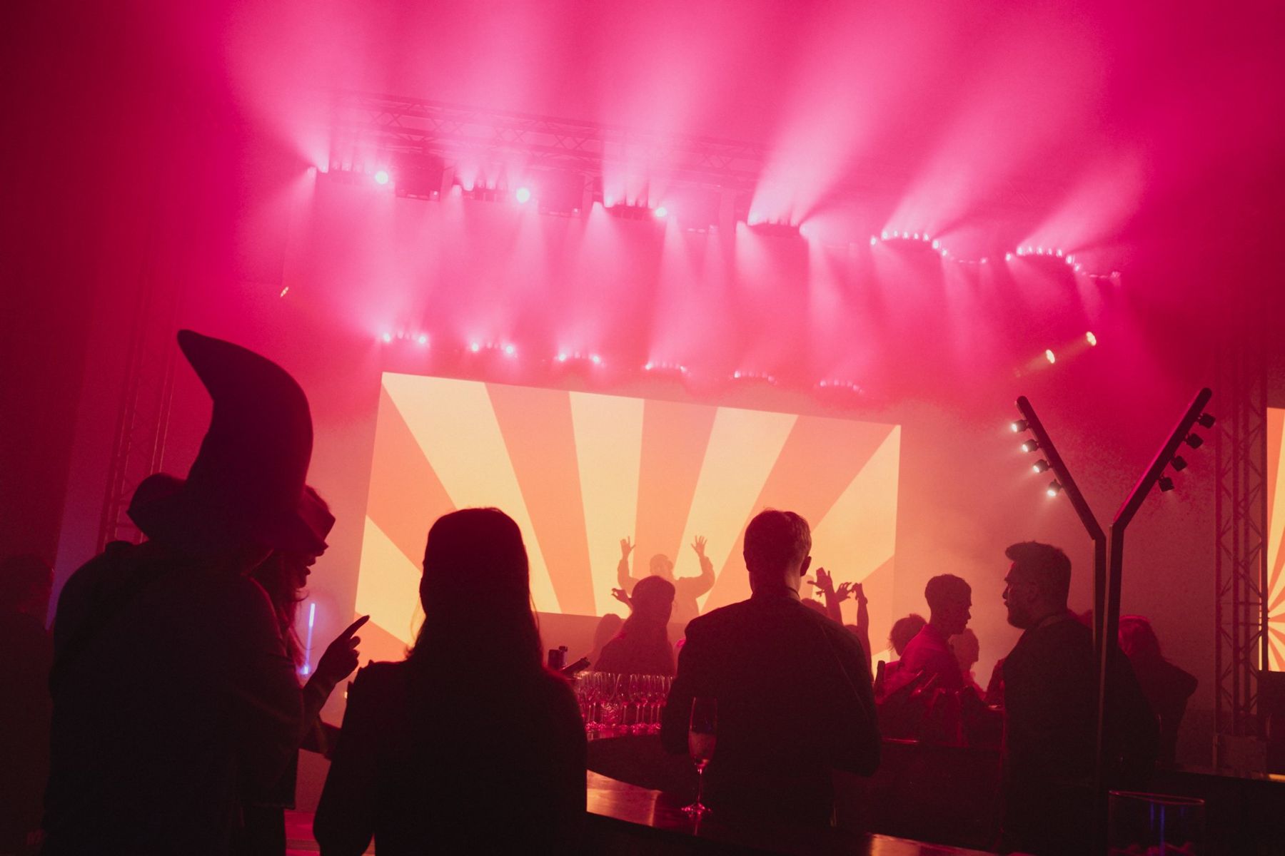 Silhouettes in costume against a pink lit stage