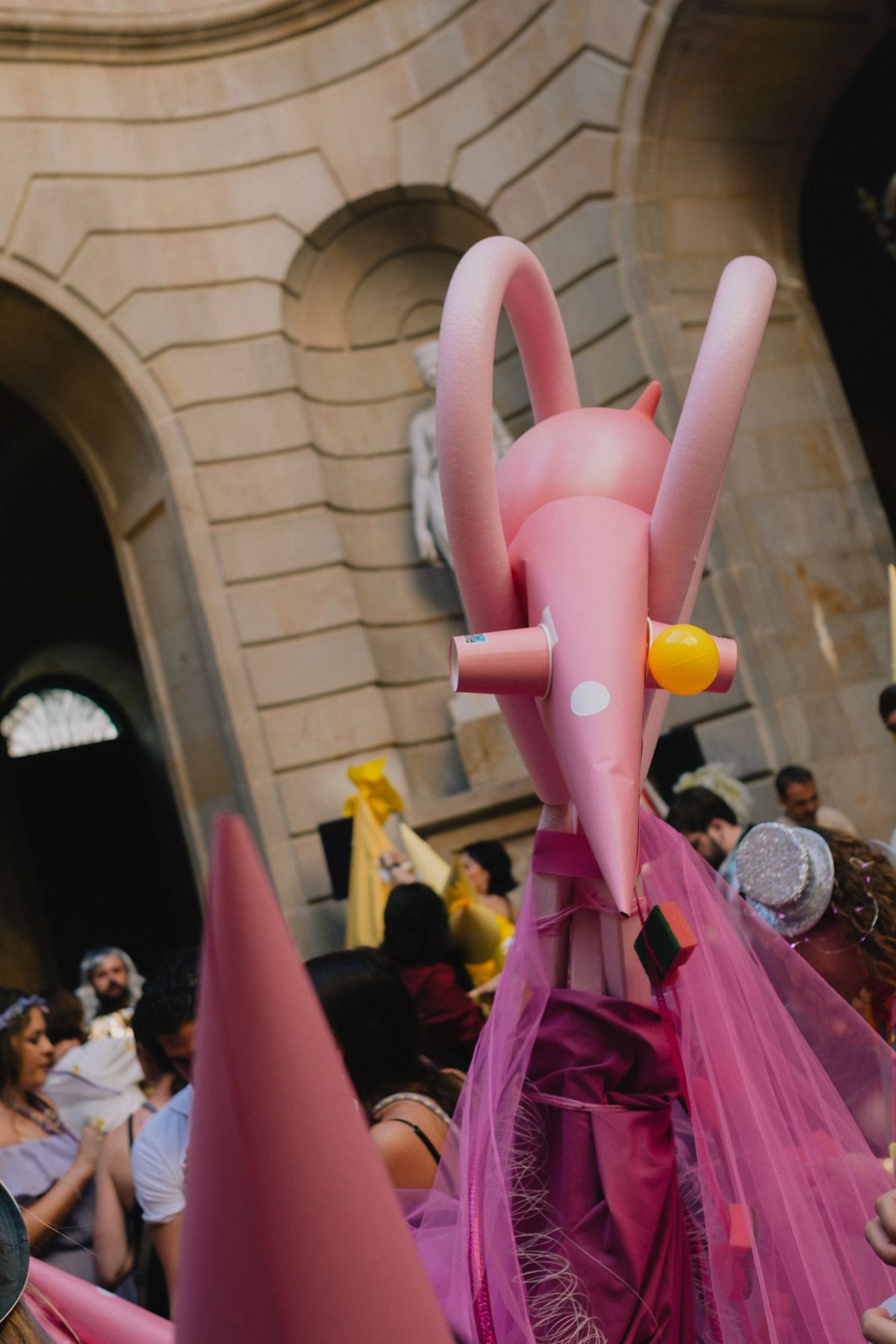 A pink creature made of cones and pool noodles, held up high