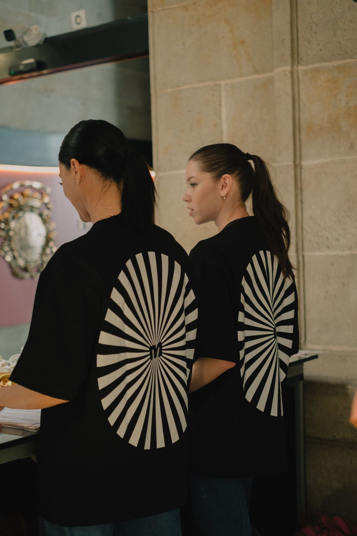 Two crew members setting up a table, the sunburst on their backs