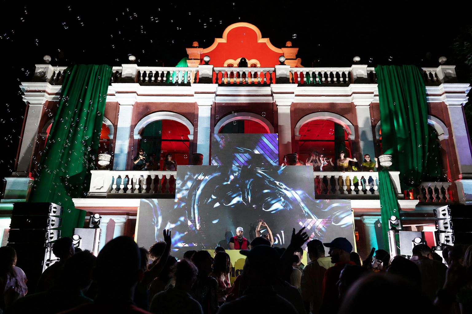 The castle lit red and green with a light show over a crowd