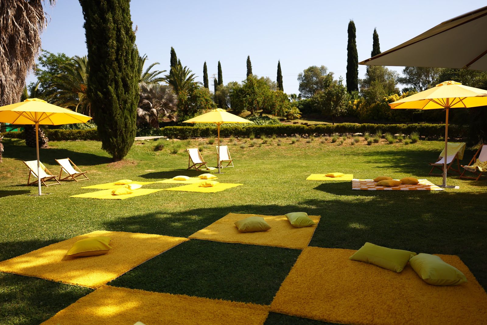 A yellow and green checkerboard on the lawn with parasols and deck chairs