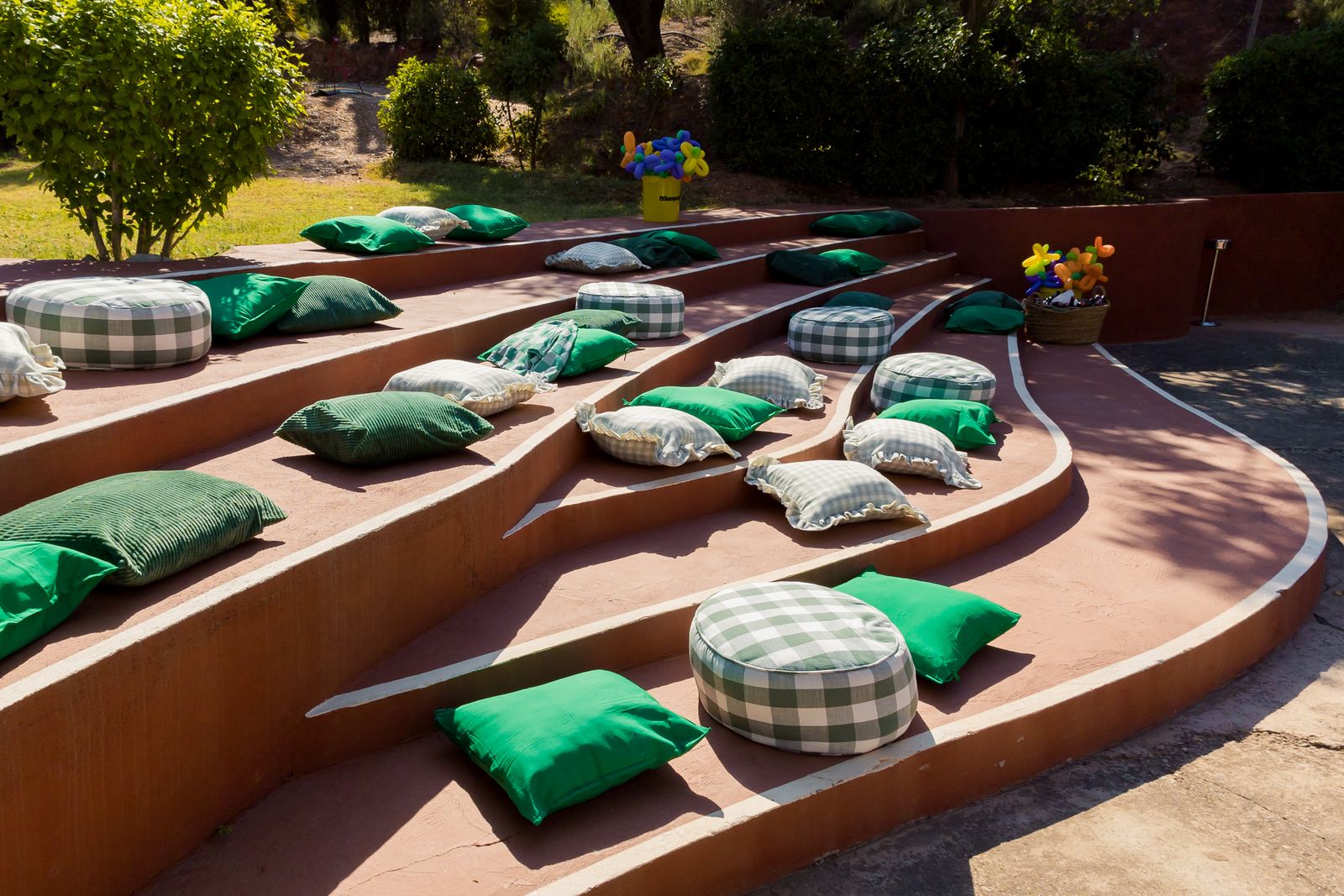 Green and checked cushions on red stone terraces under a parasol