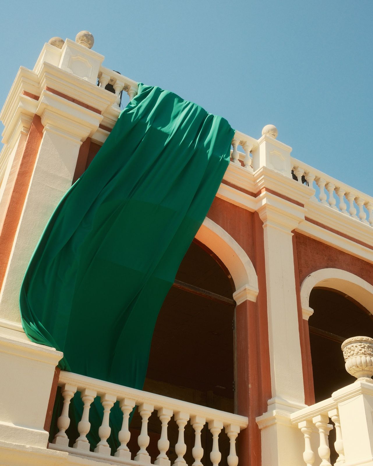 Green fabric drapes falling from the balconies of a pink castle