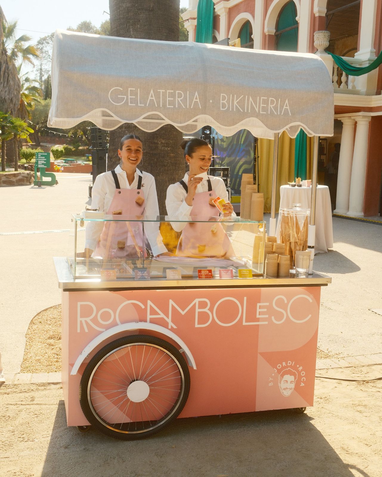 Two servers at a pink gelato cart in front of the castle