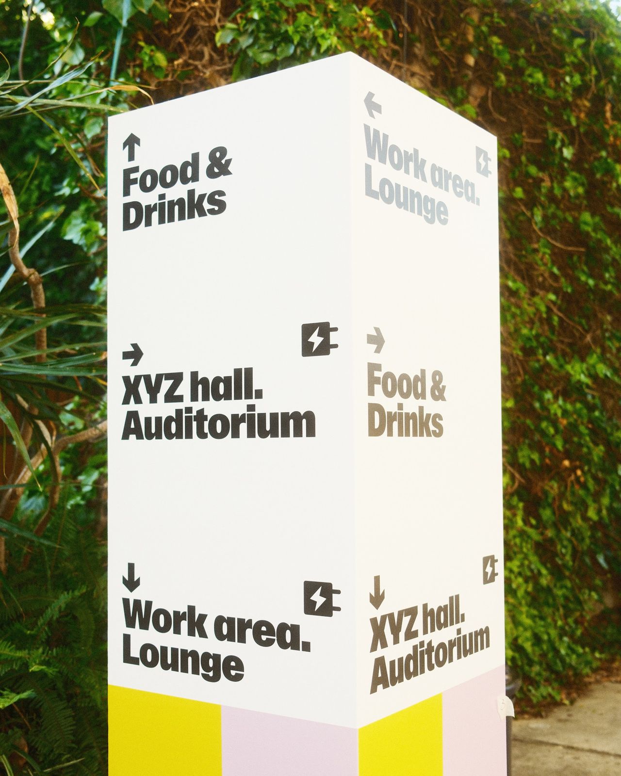 A white sign pointing to the food and drinks, the auditorium and the work area