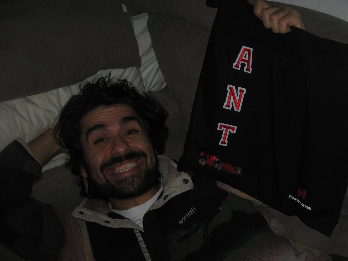 A crew member on a sofa with a tote lettered ANT