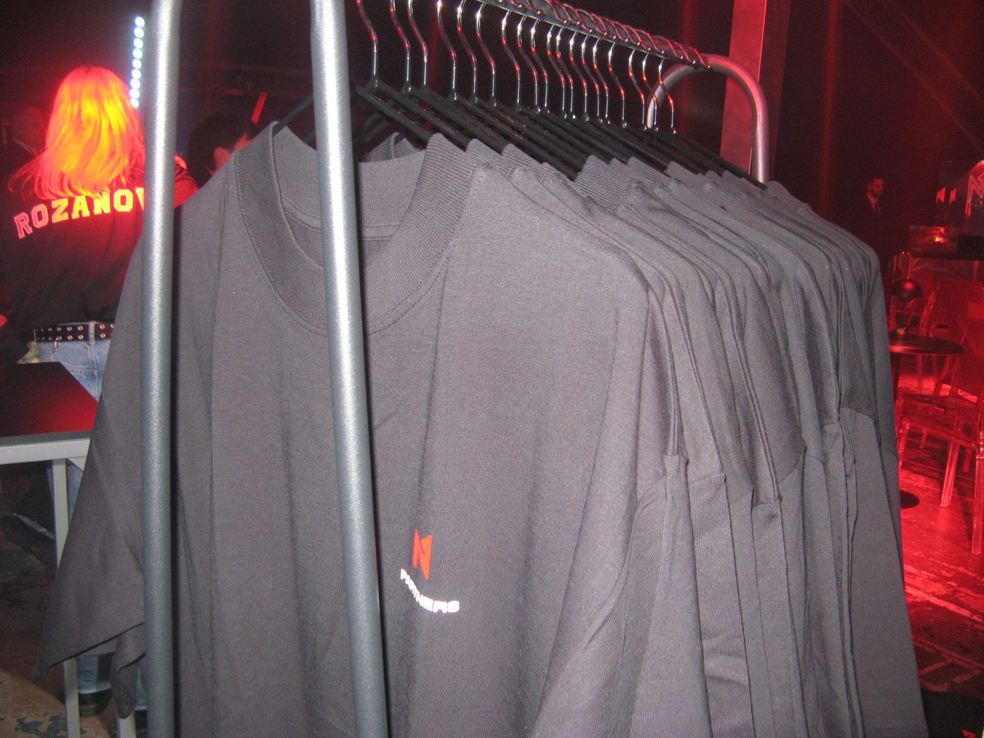 A rack of black tees under red light