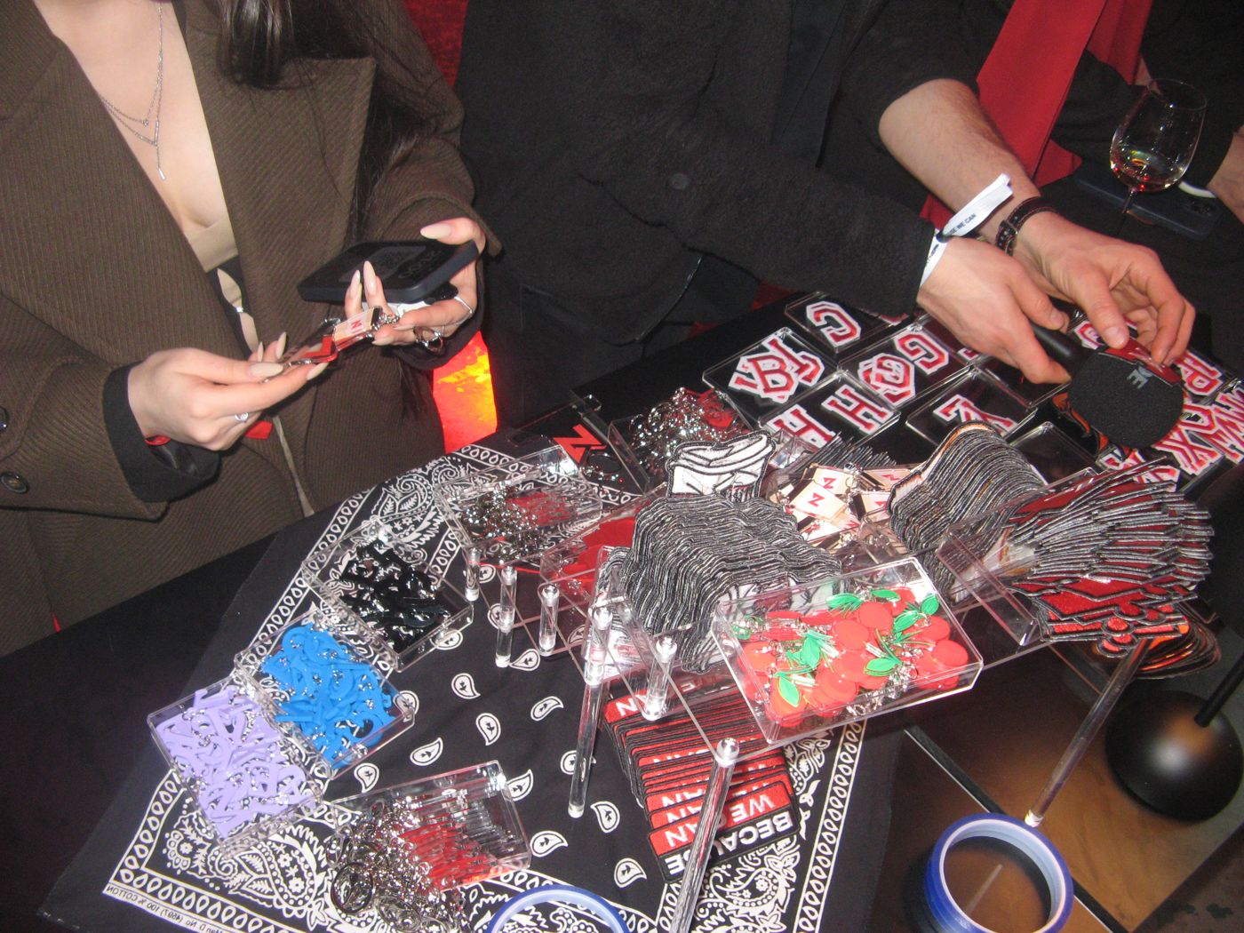 Hands picking acrylic charms from the trays