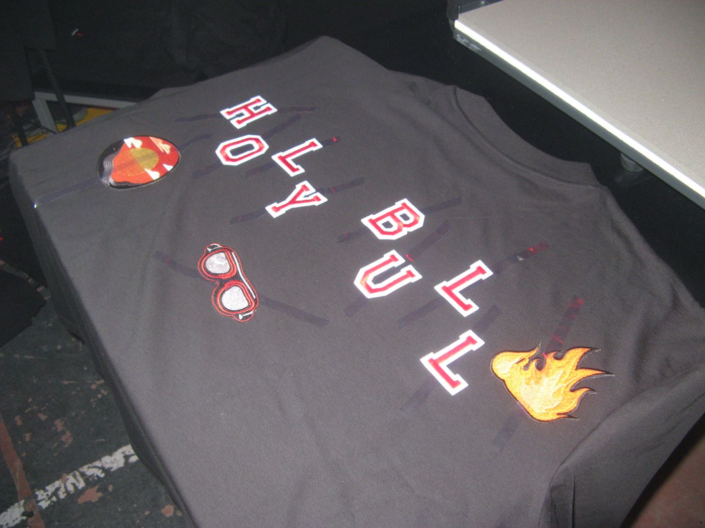 A tee spelling out letters with goggles and a flame
