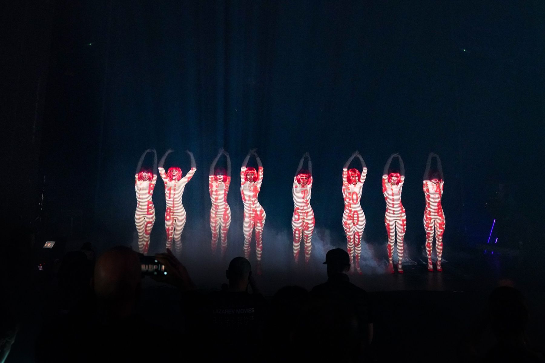 Seven dancers on a dark stage
