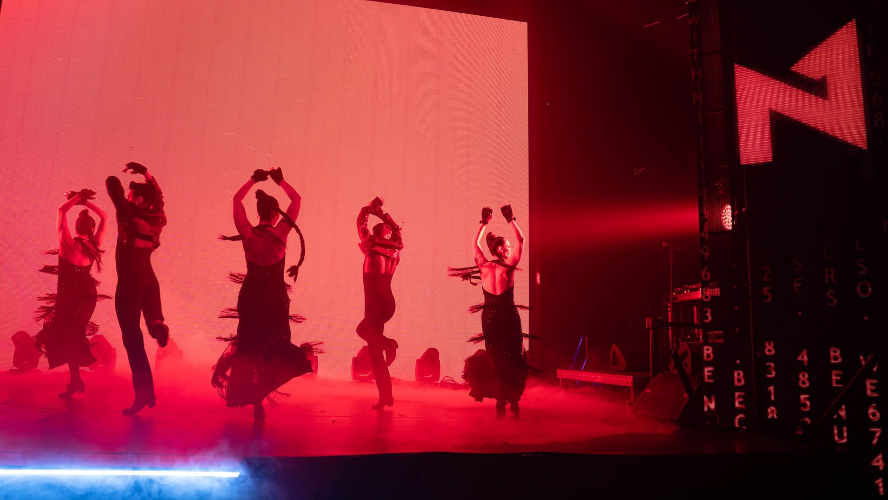 Dancers in silhouette against a red screen with the N1 sign