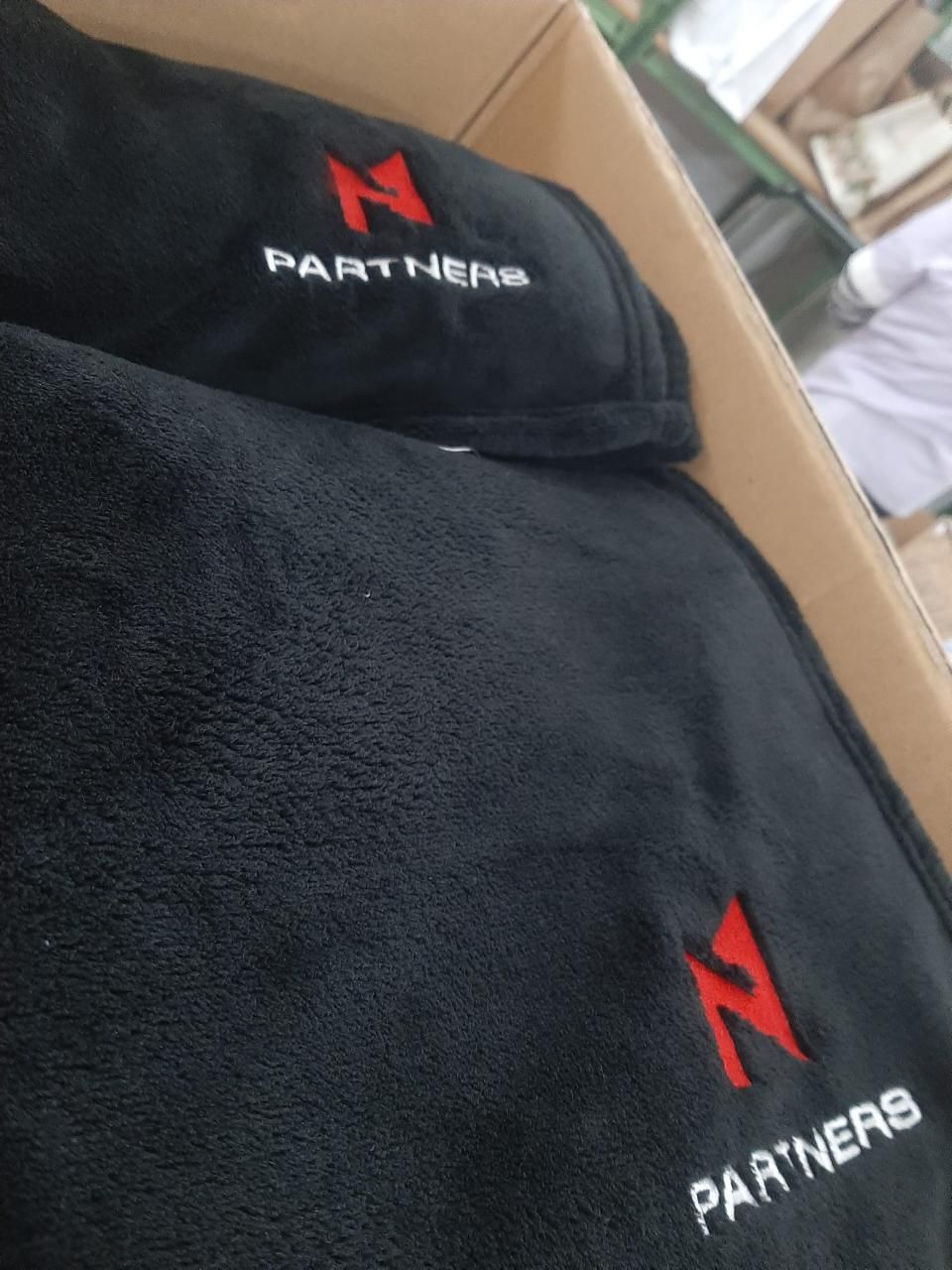 A folded black fleece blanket with N1 Partners embroidered in red
