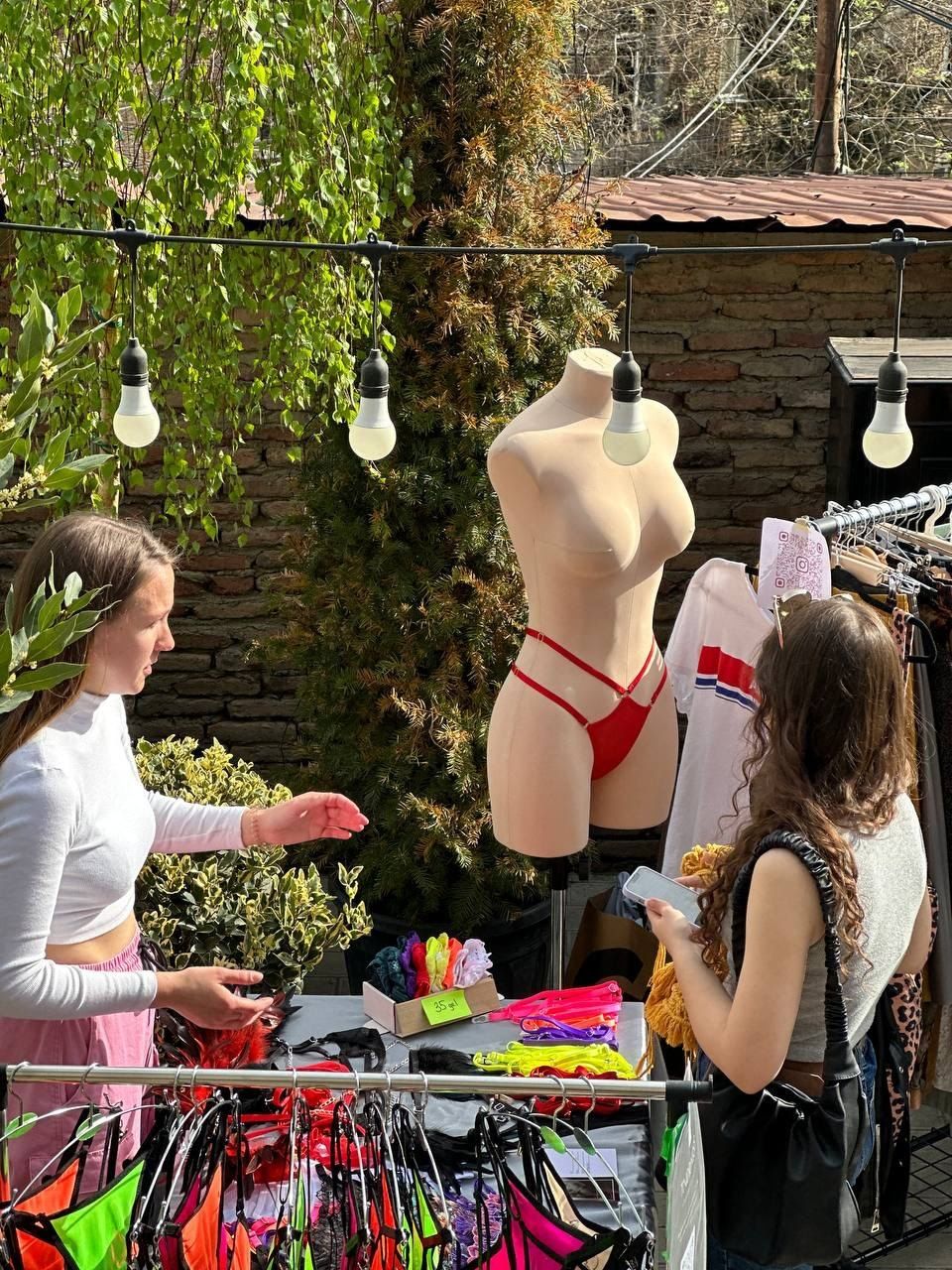 A rail of bright swimwear and a mannequin in the garden, two guests choosing