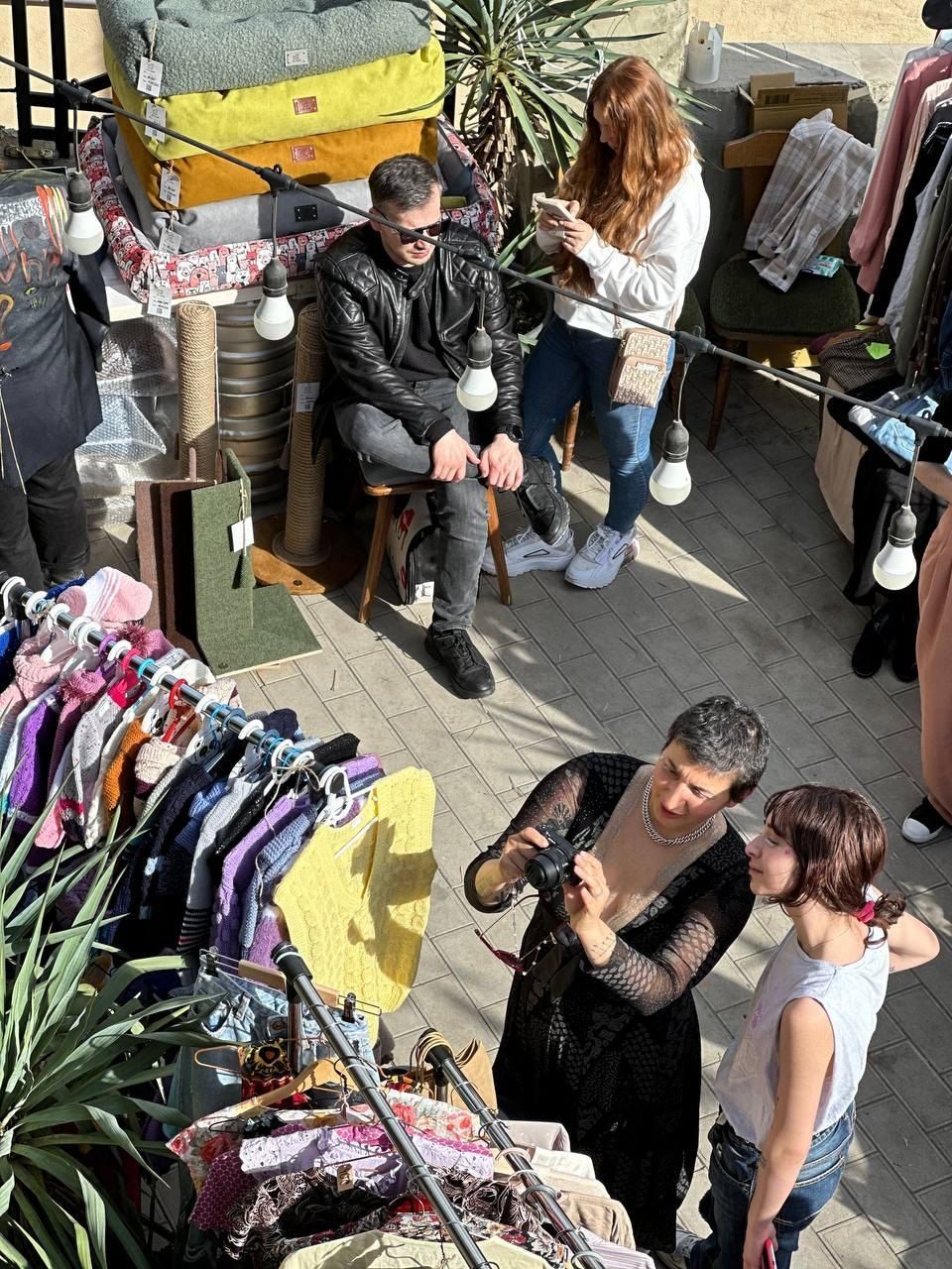 The street of rails from above: racks of vintage clothes, guests trying things on